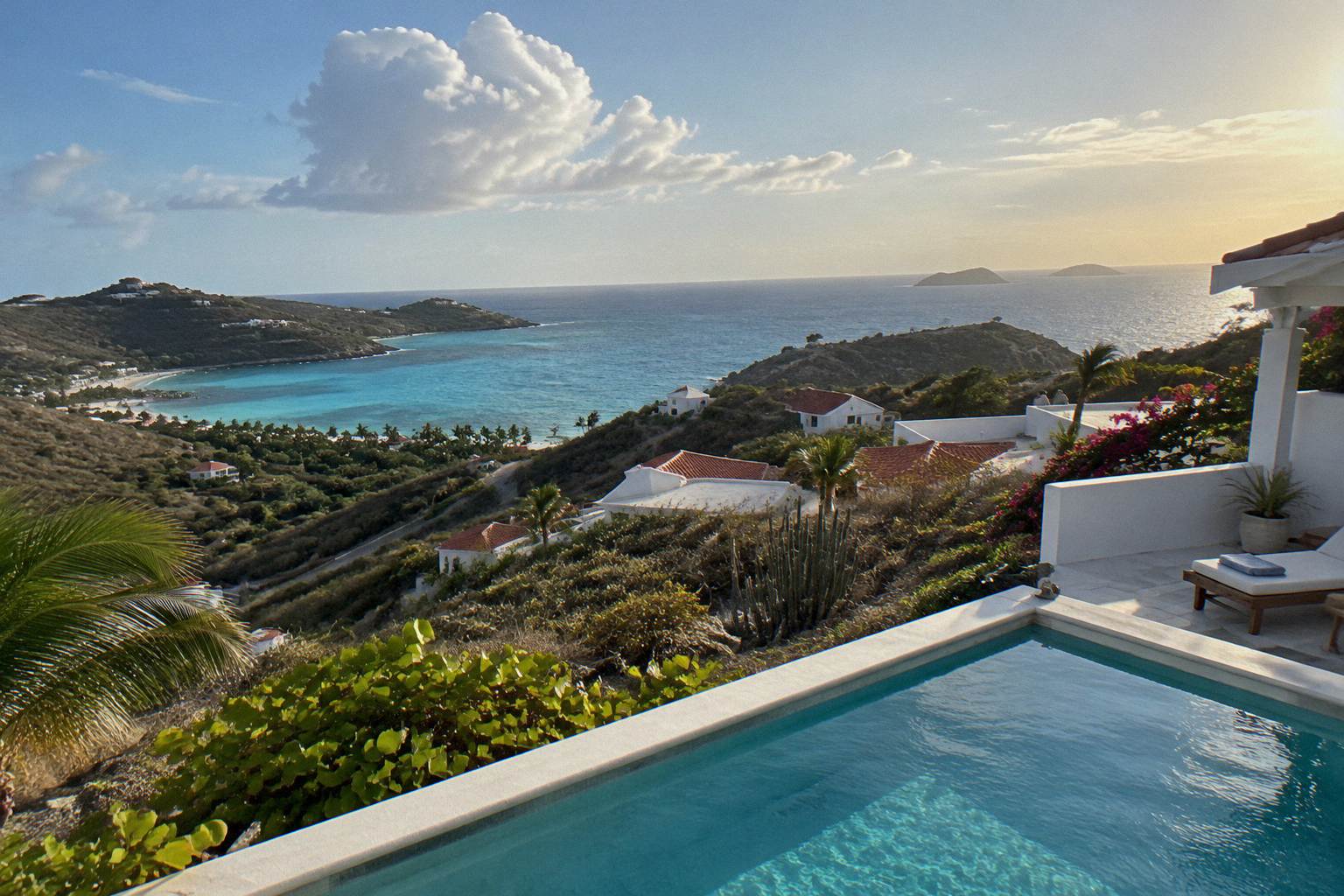 Whitewashed villa terrace with a private pool overlooking the Caribbean sea at sunset