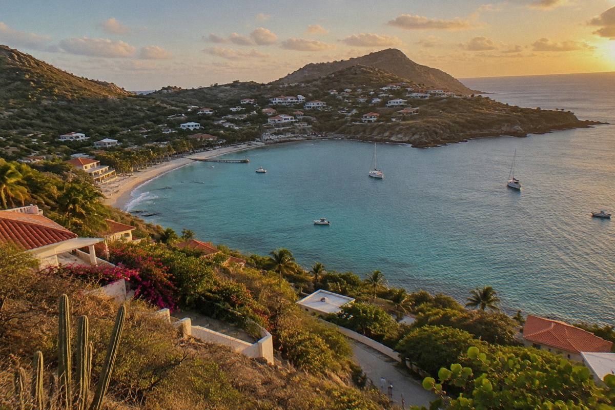 Aerial view of a curved Caribbean bay with turquoise water and wooded headlands
