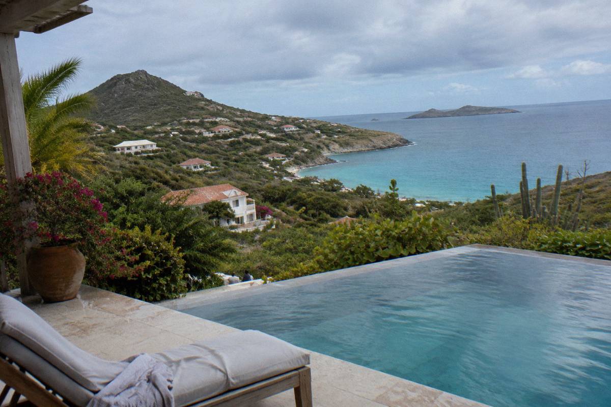 Private villa terrace with infinity pool overlooking a green hillside and sea