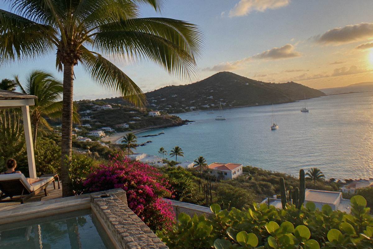 Small Caribbean hotel terrace with palms above a calm bay at late afternoon